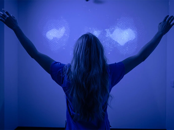 Student with arms outstretched in blue meditation room