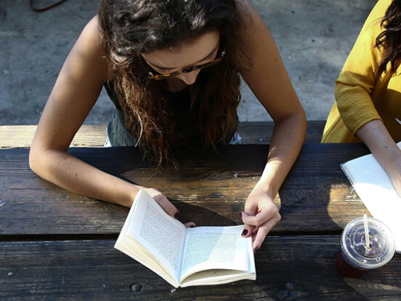 Overhead view of two women writing at a wooden table