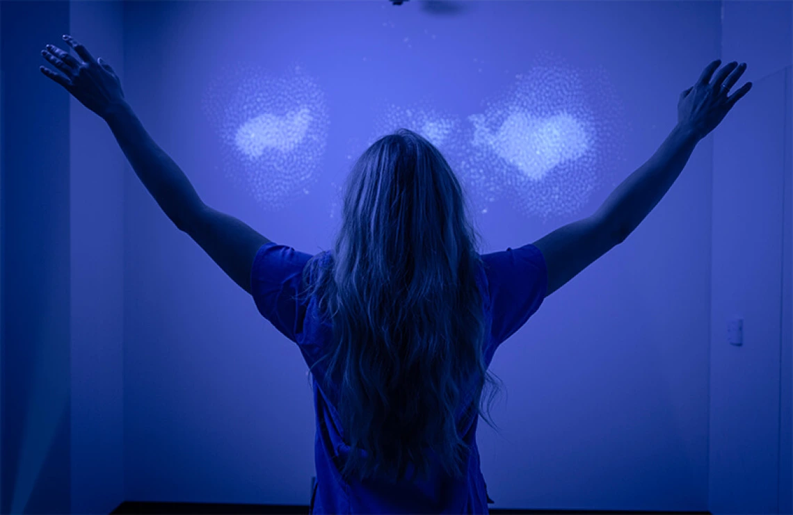 Student with arms outstretched in blue meditation room