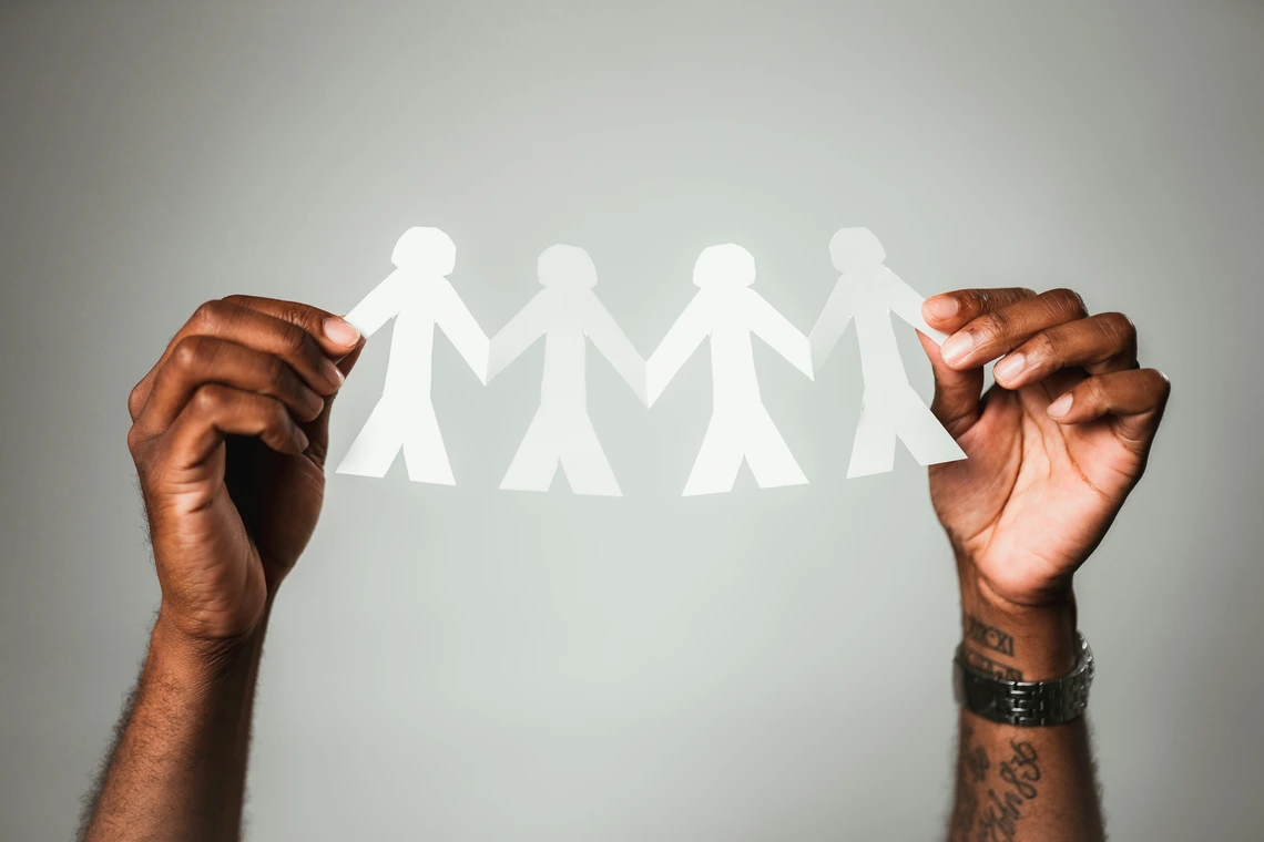 Hands holding cut-outs of people symobilizing community
