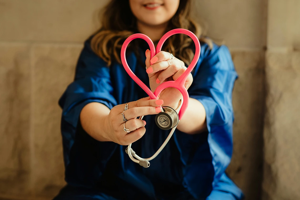 Student holds stethescope in a heart shape