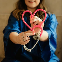 Student holds stethescope in a heart shape